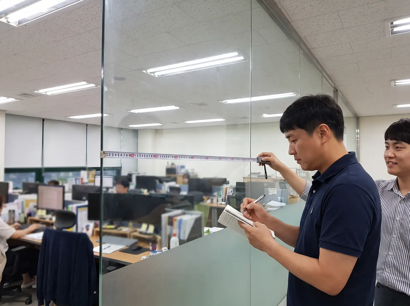 유리에 줄자를 대고 치수를 재는 모습